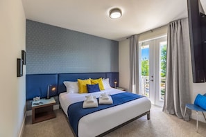A hotel room with a large bed, a nightstand, a desk, and a chair.