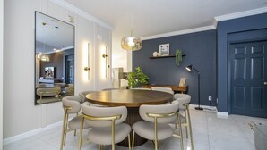 Un coin repas comprenant une table ronde, six chaises, un grand miroir et une suspension.
