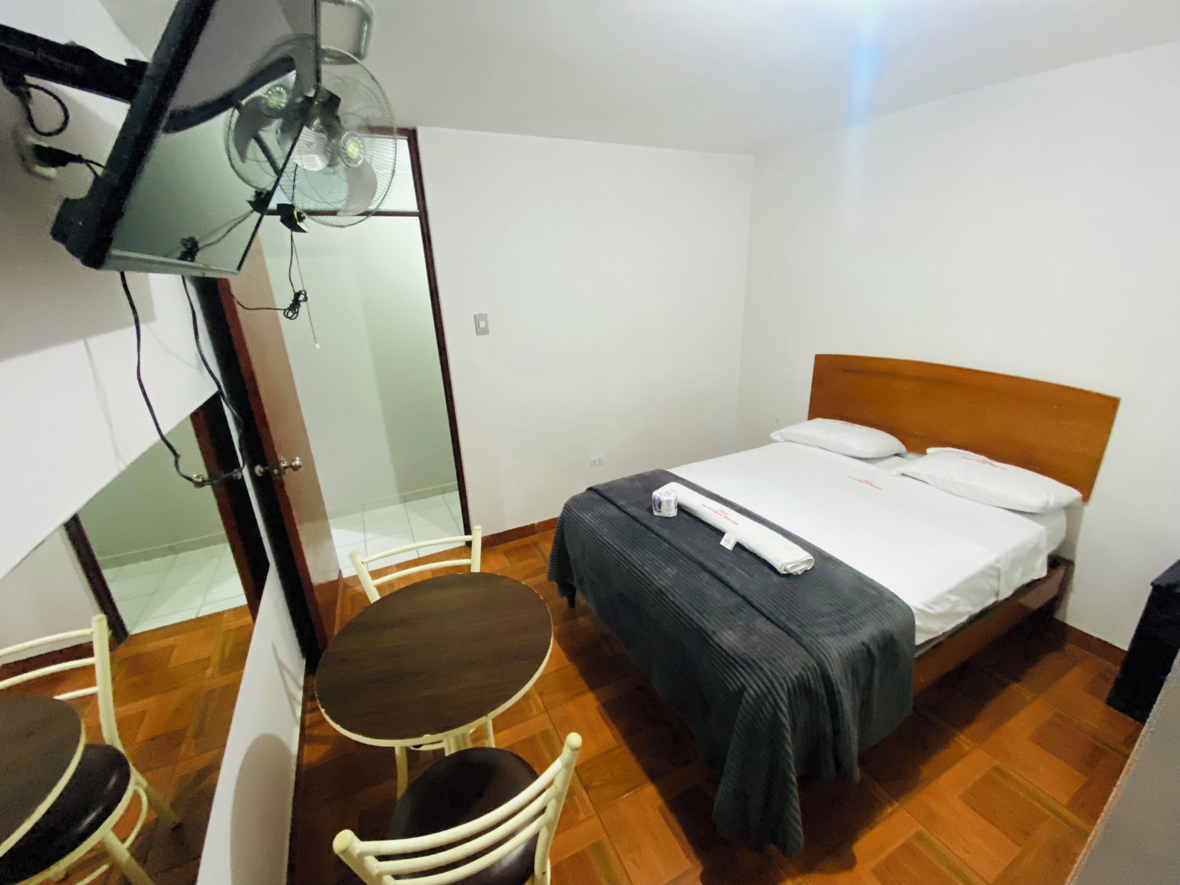 Un dormitorio con una cama, una mesita, una silla y un ventilador de techo.