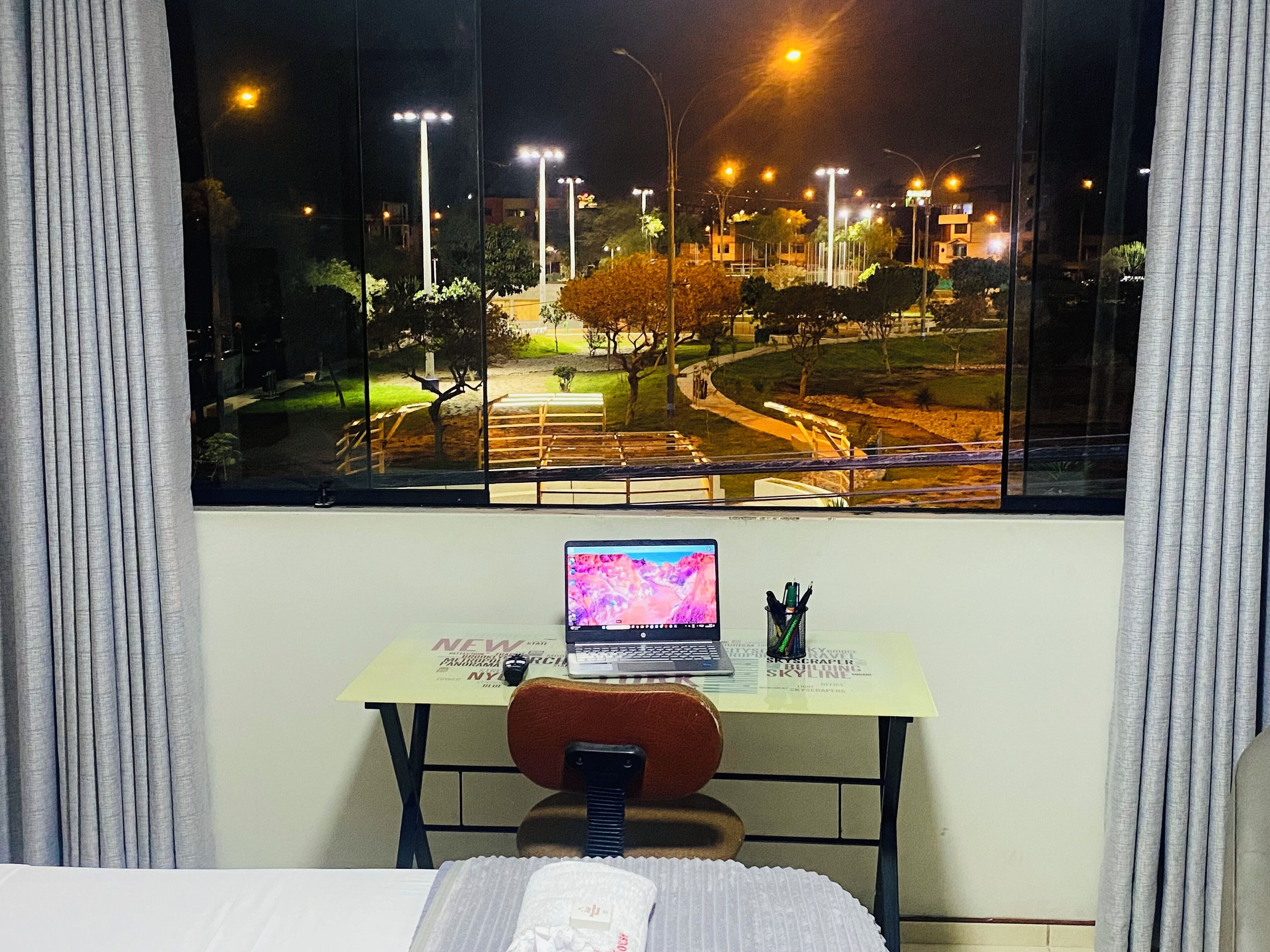 A room with a desk, a laptop, and a bed.