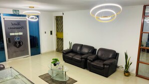 Un área de recepción con un sofá de cuero, una mesa de centro de vidrio y un mostrador de recepción.
