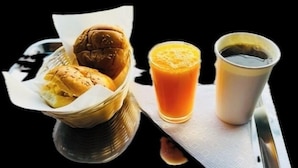 Una bandeja con una hamburguesa, un vaso de jugo de naranja y una taza de café.