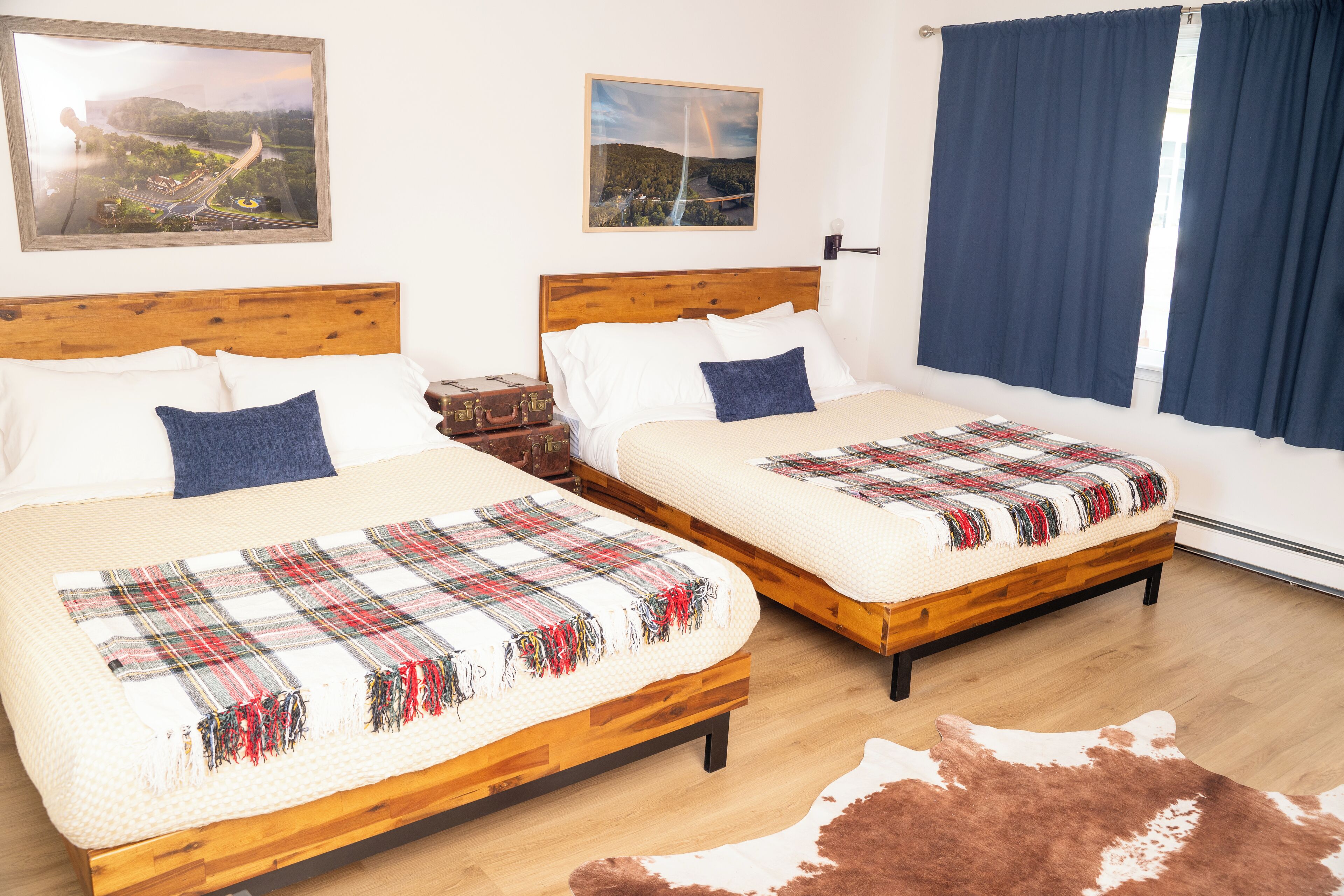 Quarto de hotel com duas camas, cabeceiras de madeira e um tapete de couro de vaca.