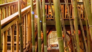 A bamboo structure with a wooden deck and a seating area. - Alpaca Treehouse in the Bamboo Forest (Atlanta)