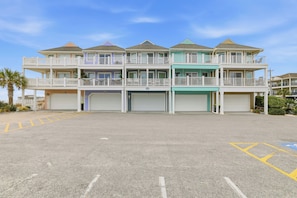 A multi-story building with balconies, a garage, and a parking lot.