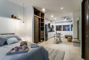Cozy retreat with a large bed, wardrobe, kitchenette, dining table, and comfortable seating.