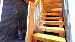 Una escalera de madera con barandilla y una pared texturizada al fondo.