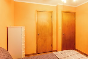 A room with two wooden doors, a white dresser, and a bed with a quilted cover. - Family-Friendly Waterloo Abode w/ Deck! (Waterloo)