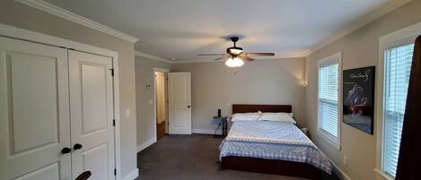 A bedroom with a bed, a ceiling fan, a rocking chair, and a door.