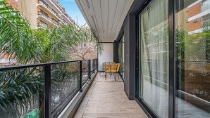 Ein Balkon mit Blick auf ein Gebäude, einem Stuhl und Topfpflanzen.
