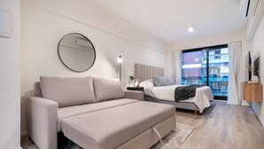 Ein modernes Schlafzimmer mit Schlafsofa, Einzelbett, rundem Spiegel und Nachttisch.