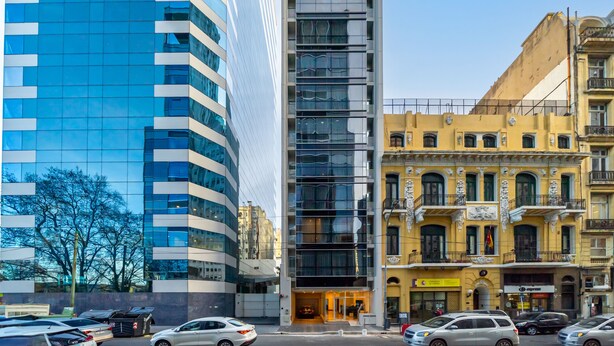 A modern building with a glass facade and a traditional yellow building with ornate balconies. - La Vie Suite Madero (Buenos Aires)