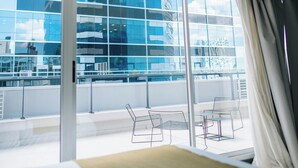 A modern hotel room with large windows, a balcony with chairs, and a view of a cityscape. - La Vie Suite Madero (Buenos Aires)
