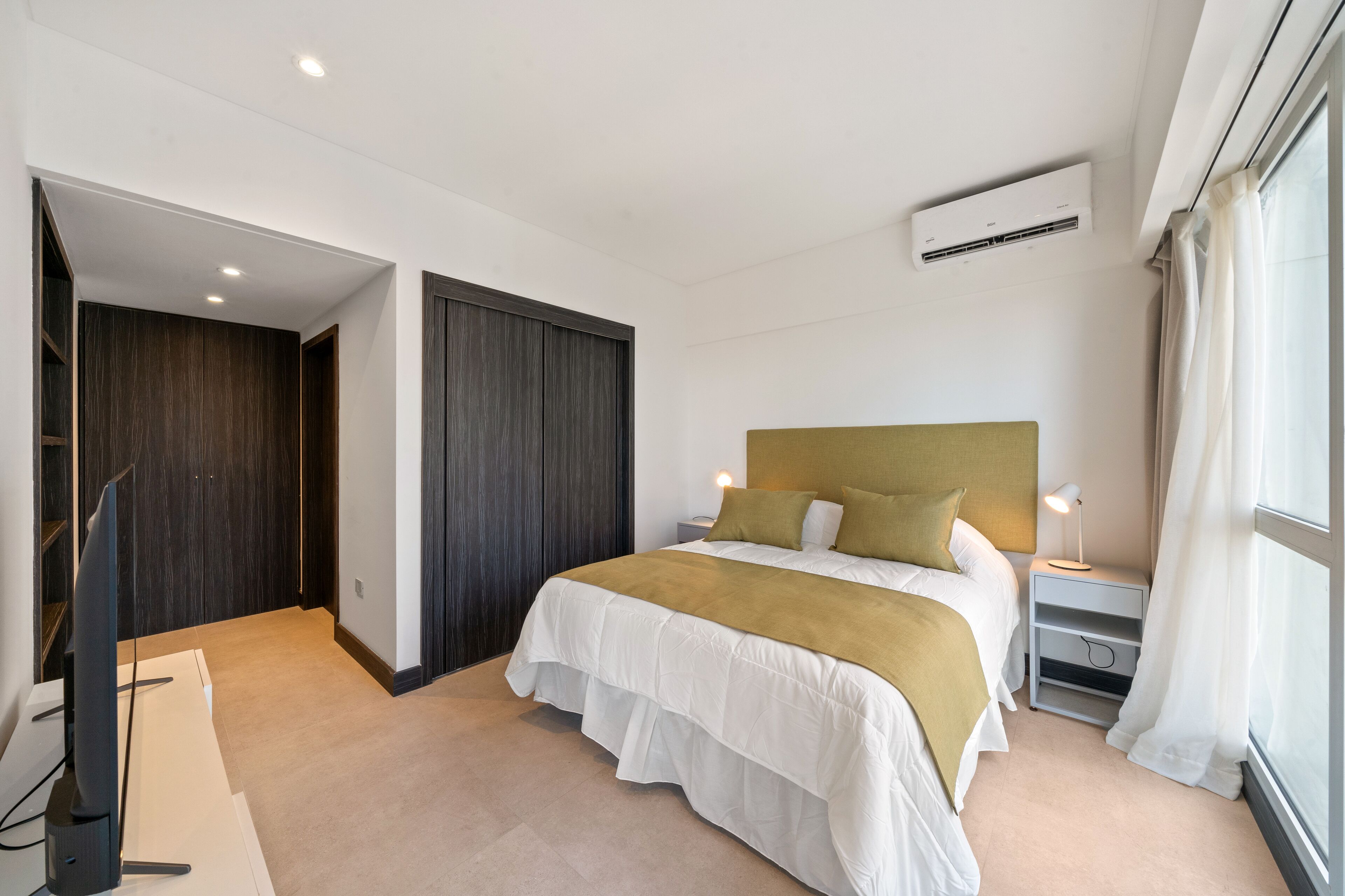 Un dormitorio moderno con una cama grande, un televisor y un armario.