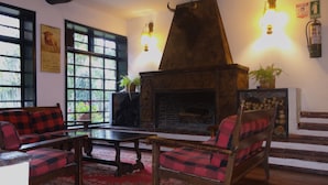 A cozy living room with a fireplace, red and black checkered sofas, a wooden coffee table, and a patterned rug. - Hacienda Suescun  (Tibasosa)