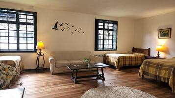 A cozy room with a sofa, two beds with checkered blankets, a coffee table, and two lamps.