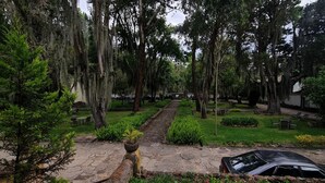 A cemetery with a paved walkway, trees, and a parked car. - Hacienda Suescun  (Tibasosa)