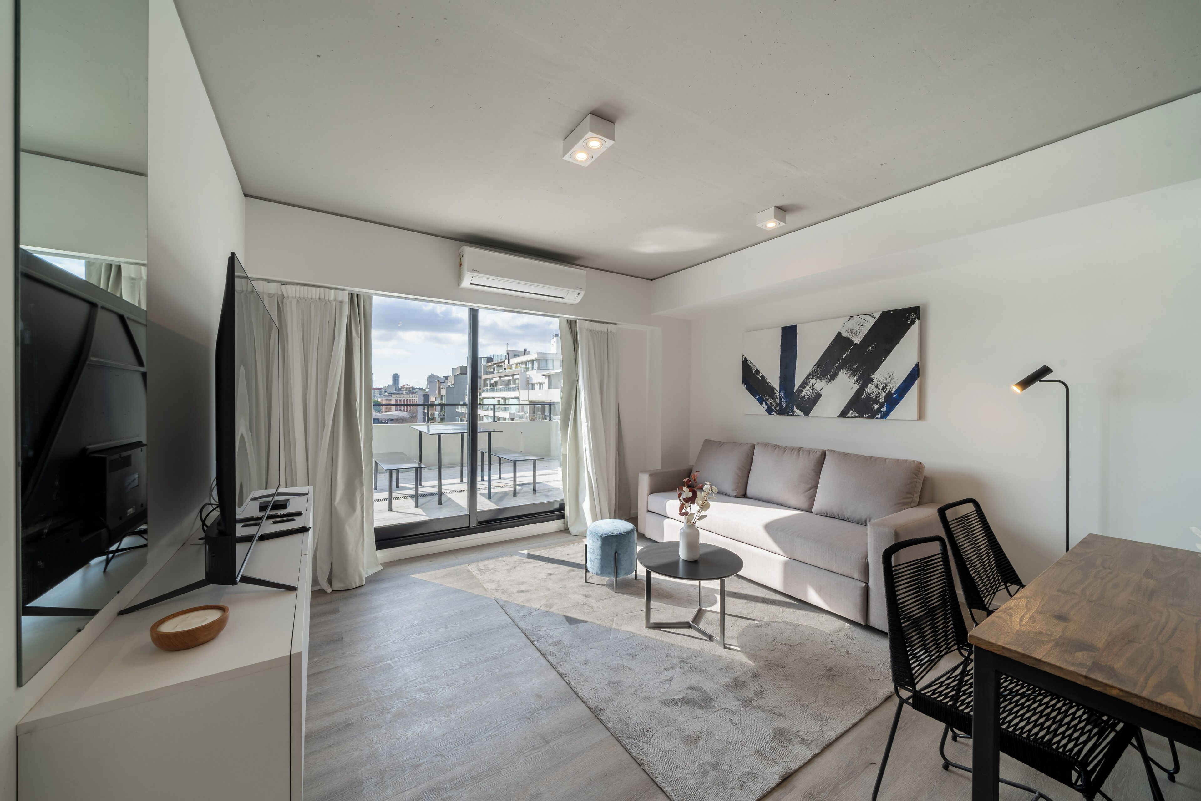 A modern living room with a sofa, a dining table, and a TV.