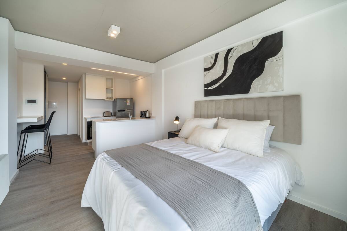 Een moderne slaapkamer met een groot bed, een bureau en een kitchenette.