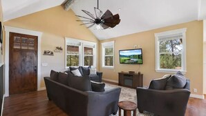 A living room with a dark-colored sofa set, a small wooden table, and a ceiling fan. - Wandering Pines - Scenic and peaceful getaway (Pine)