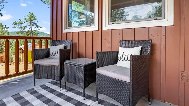 A wooden porch with wicker chairs and a checkered rug. - Wandering Pines - Scenic and peaceful getaway (Pine)