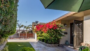 A residential property with a well-maintained garden, a patio area, and a house entrance with a door and window. - Charming Coastal Home – Carmel, Pebble Beach & Big Sur STR25-000020 (Marina)