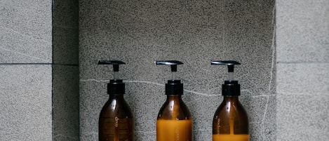Three brown bottles with black pumps in a stone wall alcove.
