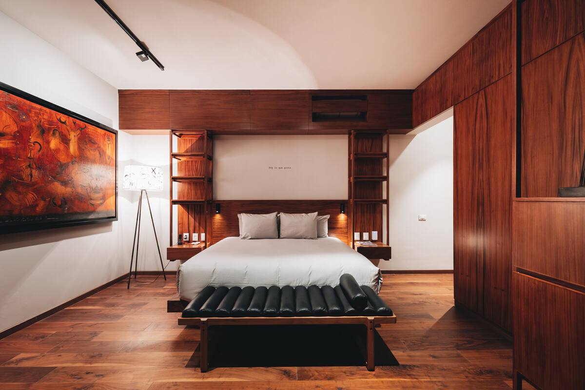 A modern bedroom with a large bed, wooden cabinetry, and a floor lamp.