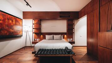 A modern bedroom with a large bed, wooden cabinetry, and a floor lamp.