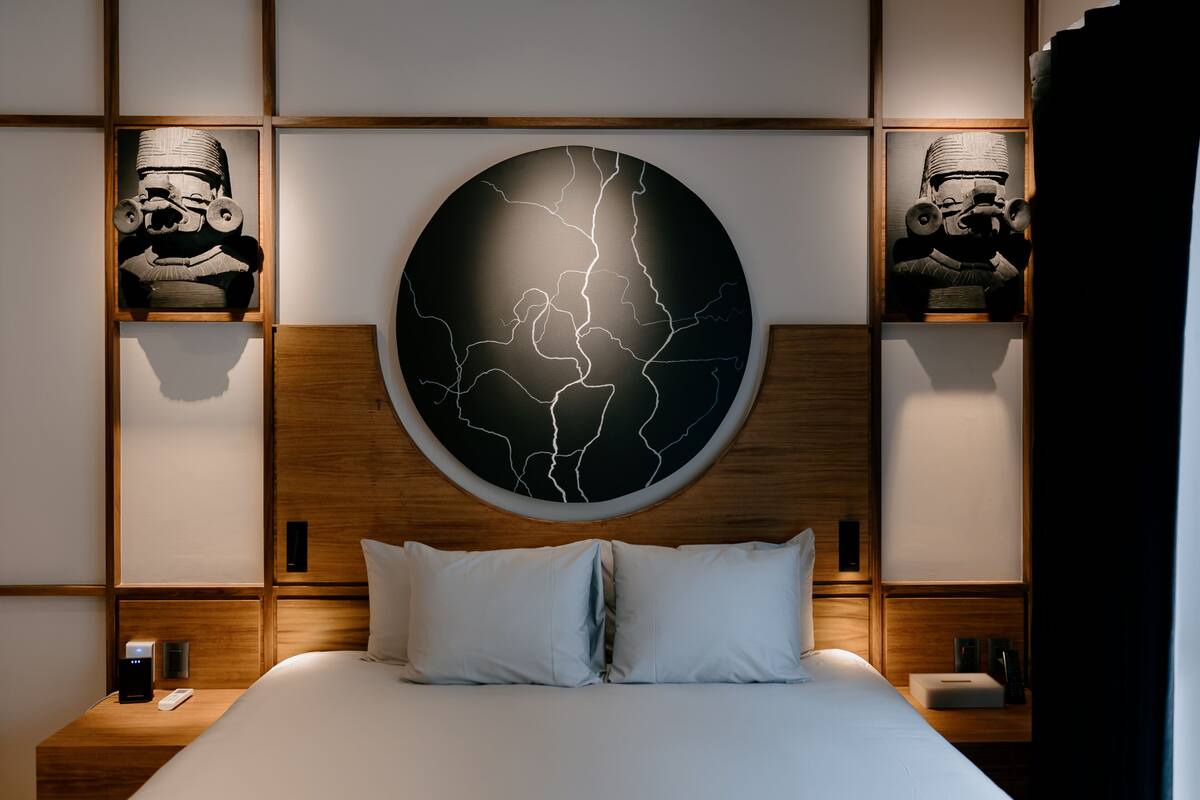 A modern hotel room with a large bed, wooden headboard, and two nightstands.