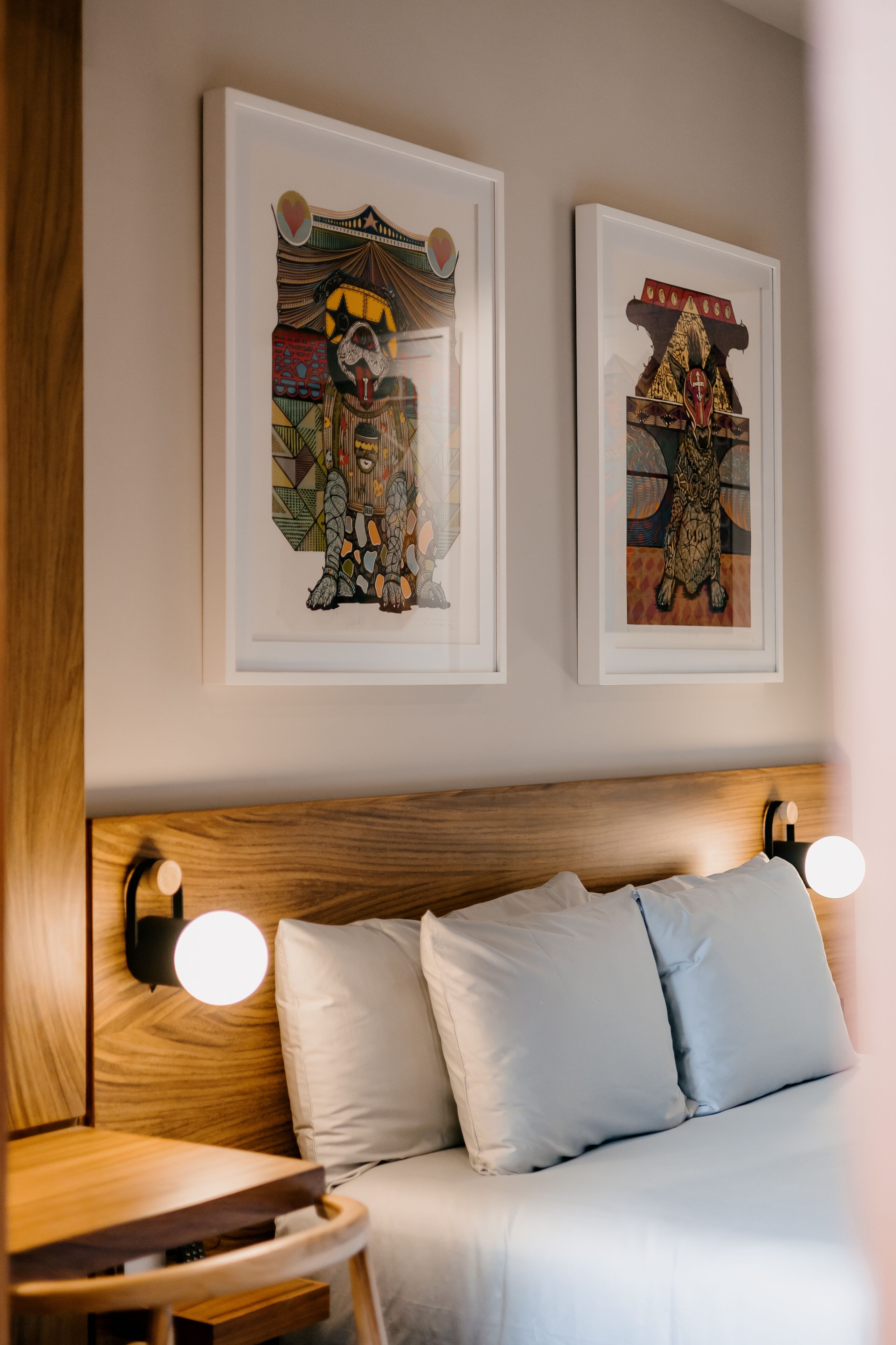A neatly made bed with white linens and two round wall-mounted lights.