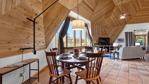 A dining area with a round table and chairs, a ceiling fan, and a view of the outdoors through large windows. - The Turtle Shell Dome (Berthoud)