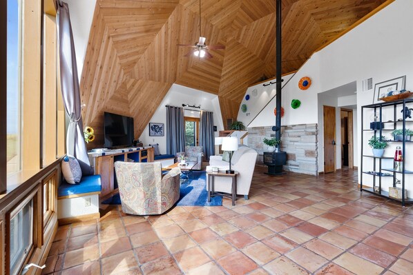 A spacious living area with a high ceiling, a large TV, and a cozy seating arrangement.