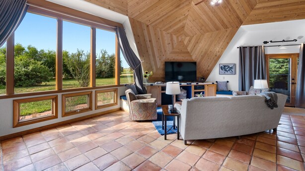 A spacious living area with a large window, a ceiling fan, and a TV. - The Turtle Shell Dome (Berthoud)