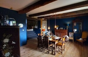 Enjoy meals in this cozy dining area with a wooden table and matching chairs, surrounded by exposed beams and a blue wall.