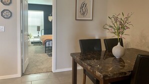 A dining area with a marble table and chairs, a vase with flowers, and a framed botanical print on the wall. - Cozy home # Safe Neighborhood & Pet Friendly (Lubbock)