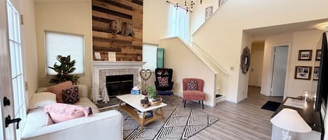 A spacious living area with a fireplace, a staircase, and a cozy seating arrangement.