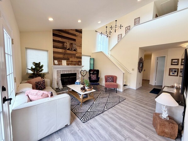 A spacious living area with a fireplace, a staircase, and a cozy seating arrangement.