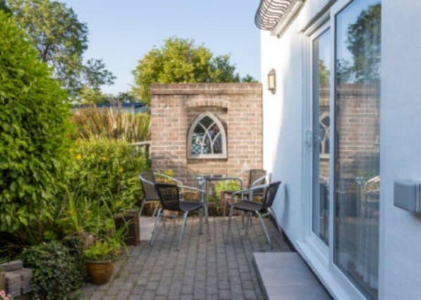 Enjoy outdoor dining or relaxation in this serene patio area with a brick wall, potted plants, and a comfortable seating area.