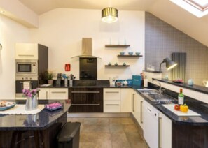 Kitchen features a central island with a sink and range hood, cabinets, and a microwave.