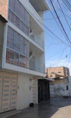 Stunning two-story building with a flat facade and a balcony on the upper floor, featuring a large gate at the entrance.