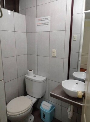 Features a compact bathroom with a toilet, sink, and tiled walls and floor.