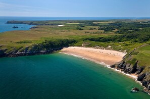Une vue aérienne d’une zone côtière avec une plage, des falaises et un ciel dégagé.