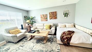 Een woonkamer met een bank, een salontafel, een bed en kunstwerken aan de muren.