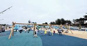 Un parque infantil con columpios, tobogán y estructura para escalar.