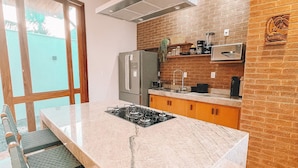 Una cucina moderna con isola centrale, elettrodomestici in acciaio inossidabile e una parete decorata con mattoni.