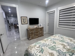 A bedroom with a bed, a dresser, a television, and a door with blinds. - Coastline Marine Extremes ChillN (Marathon)