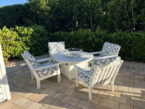Un patio con una mesa redonda y cuatro sillas, rodeado de follaje.