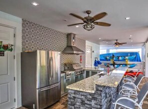 A kitchen with a granite countertop, stainless steel appliances, and a central island with seating.