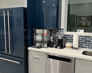 Une cuisine moderne équipée d’une machine à café intégrée, d’une bouilloire et d’un moulin à café.